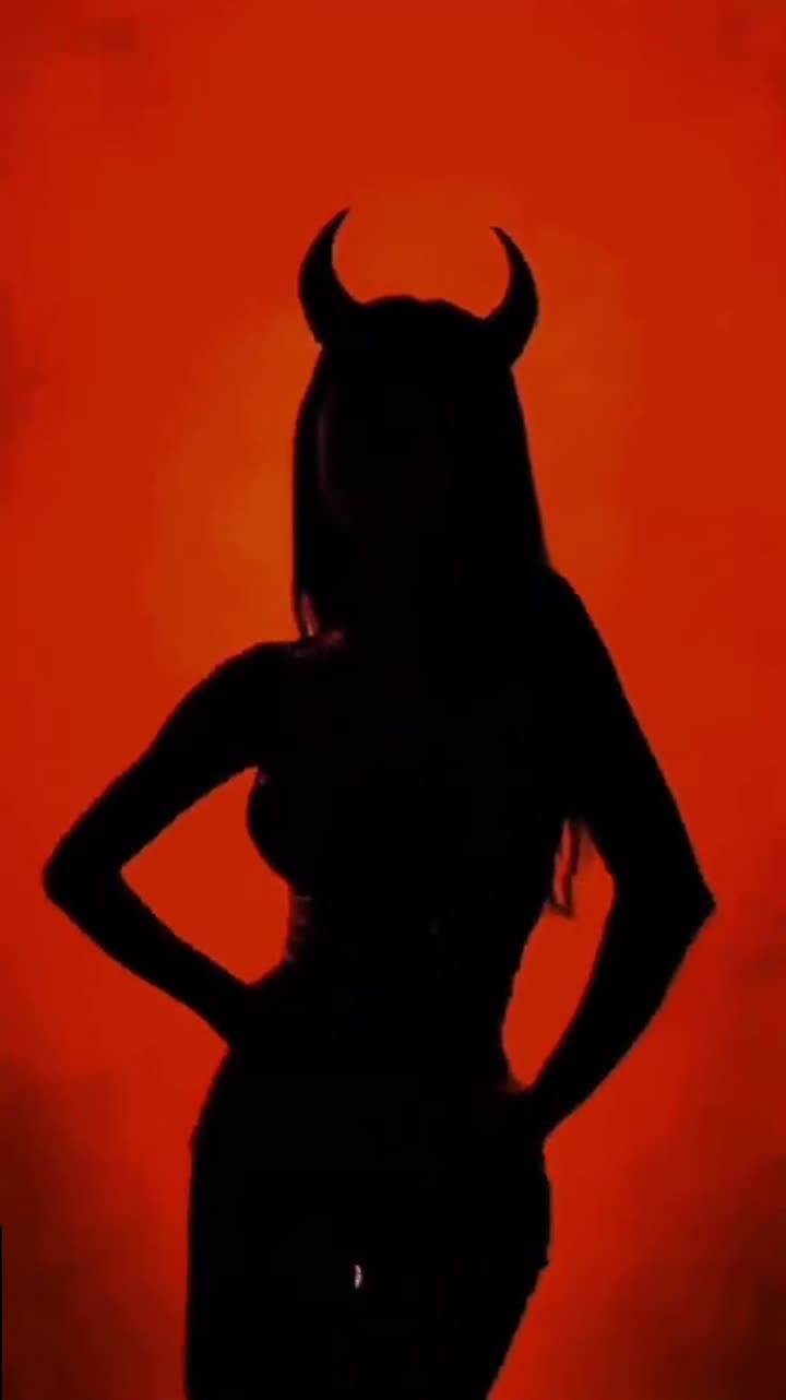 A woman in silhouette against a field of burning red light.